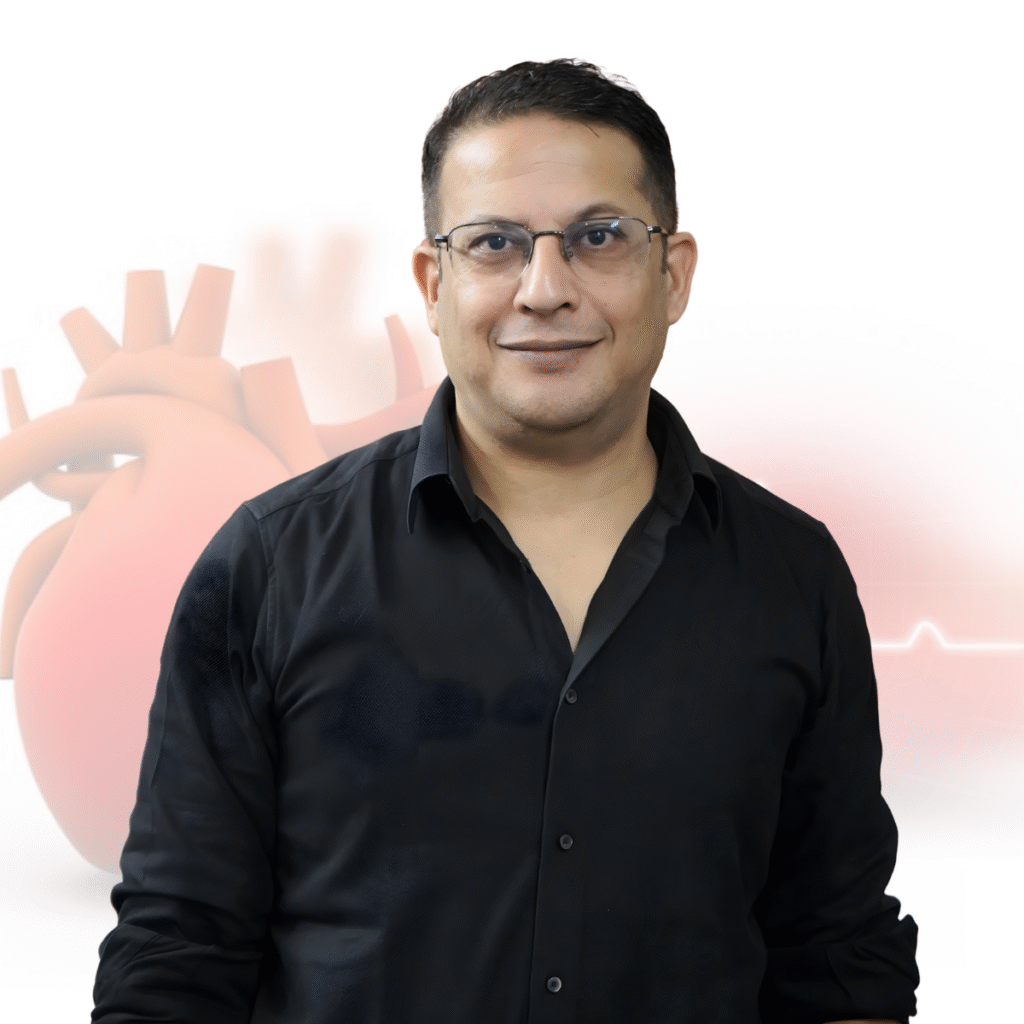 A man wearing glasses and a black shirt standing in front of a medical-themed background with a heart illustration.