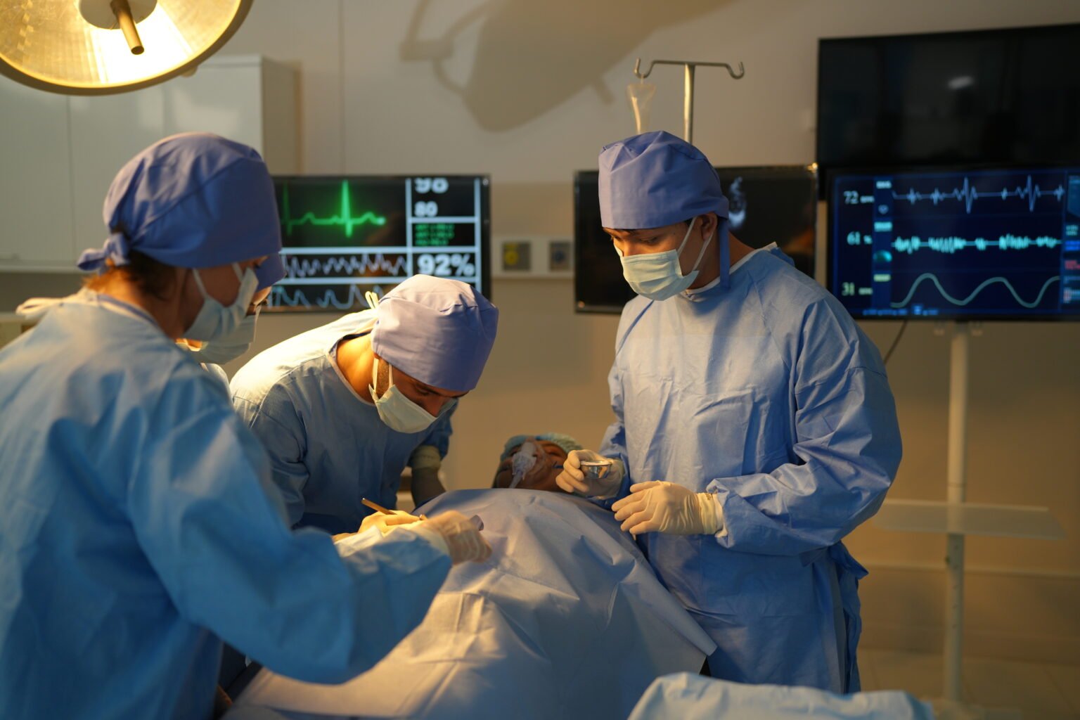 Cardiac surgeons performing surgery under monitoring screens in an advanced operation room at Cardiac Care Associates, best cardiac care centre in Bhopal.